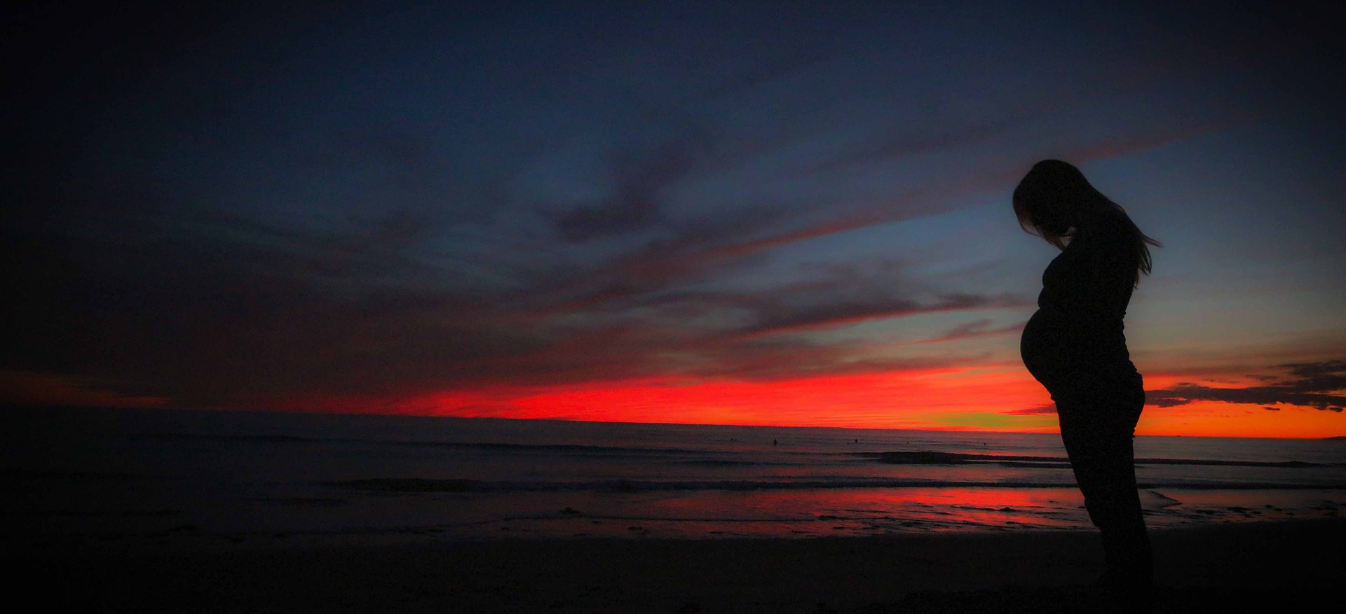 Pregnant woman on the beach at sunset