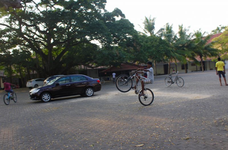 Young men play on bikes in Galle