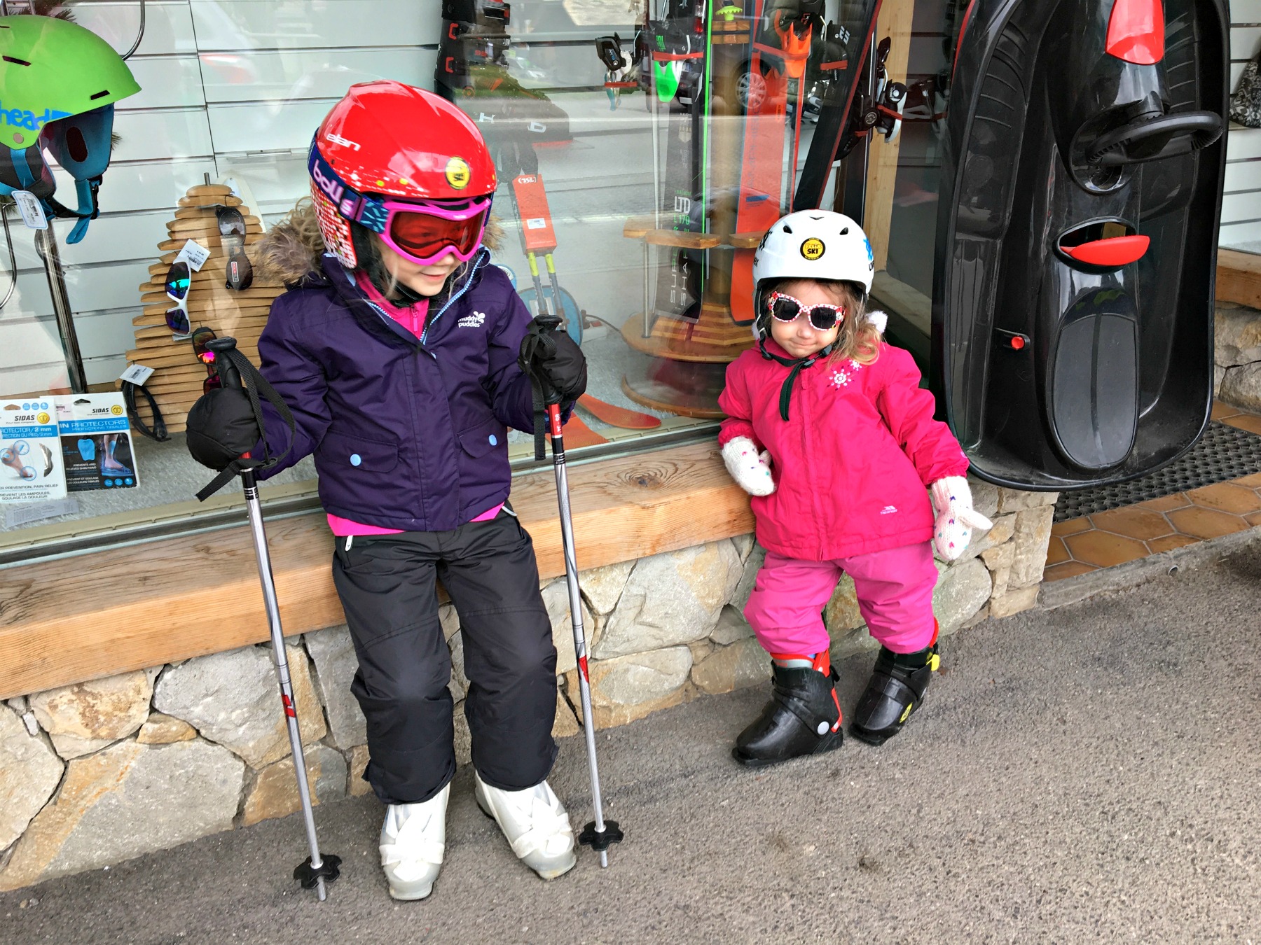 Two children in ski clothing having hiring ski equipment for a family ski holiday
